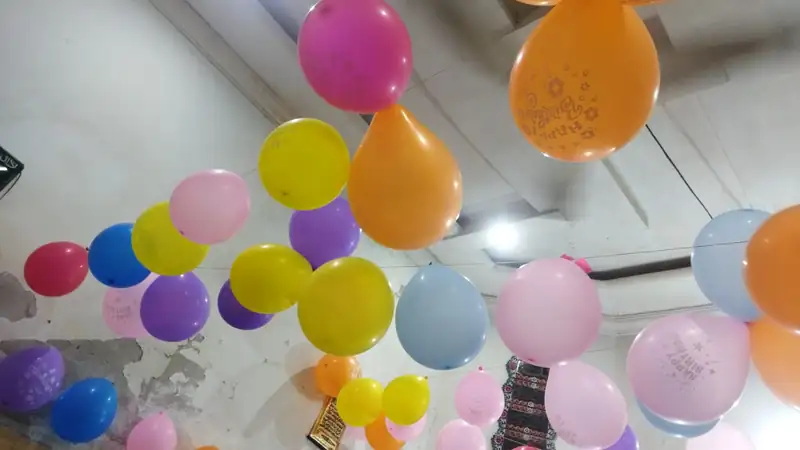 A room ceiling covered with colorful party balloons.