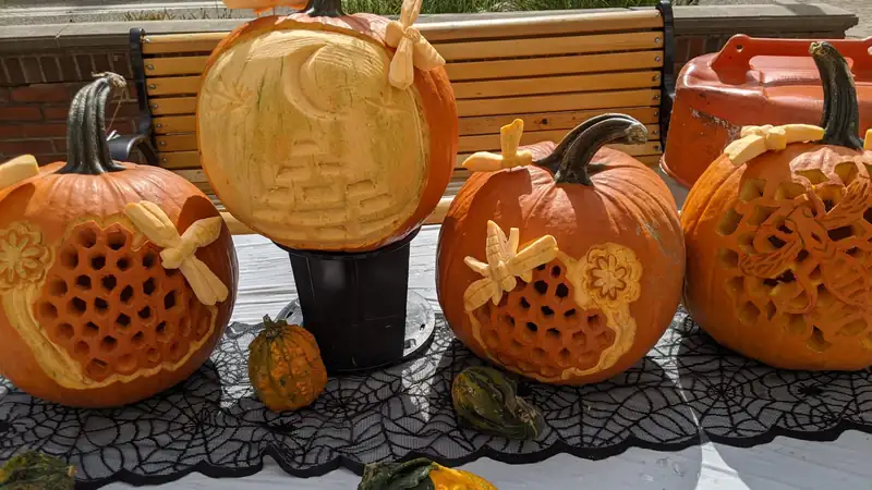 Intricately carved pumpkins displayed on a table outdoors.