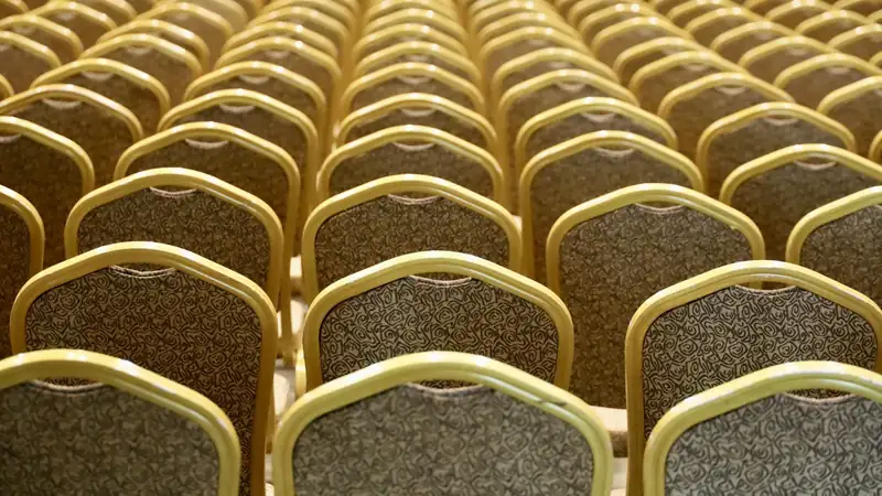 Rows of gold banquet chairs set up for an event.