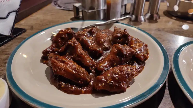A plate of glossy barbecue chicken wings on a table.